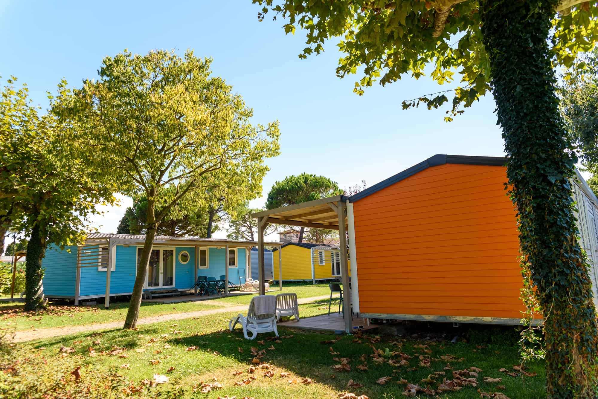 Gemütliche bunte Wochenend-Cottages im Campingplatz mit viel Natur und Schatten, ideal für Familien und Naturliebhaber, in ruhiger Umgebung.